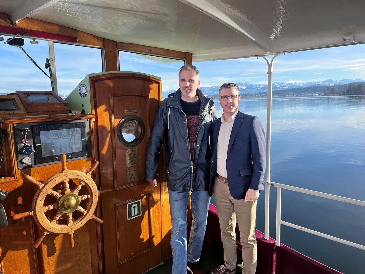 Die Kapitäne der SGG: Geschäftsführer Andy Ehrentraut (links) und VR-Präsident Gianluca Di Modica. Zwei Männer posieren an Bord eines Schiffs für die Kamera. Links ist ein altmodisches Steuer aus Holz zu sehen.